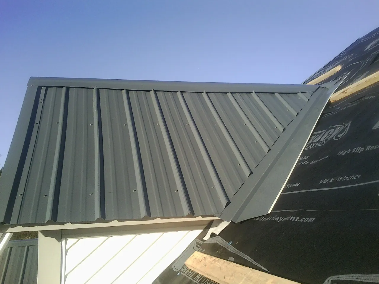 Gray metal roof panels going on over a garage gable in Indianapolis