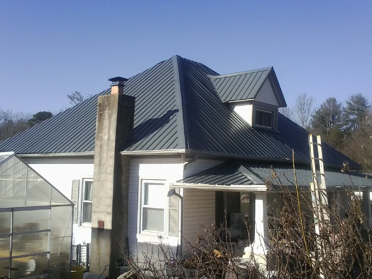 Dark blue standing seam metal roof on a white farmhouse with dormer — Slate & Tile Roof Repair by Roofing Brothers in Indianapolis