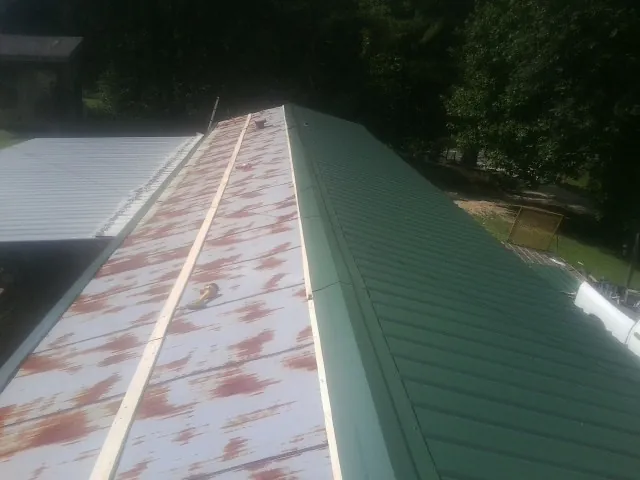 Old rusted panels beside newly installed green metal roofing — Wind Damage Roof Repair by Roofing Brothers in Indianapolis