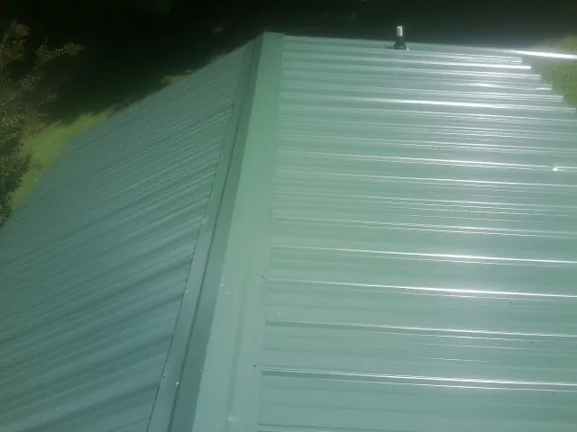 New green metal panels meeting at the ridge of a roof — Flat Roof Repair work by our crew in Indianapolis