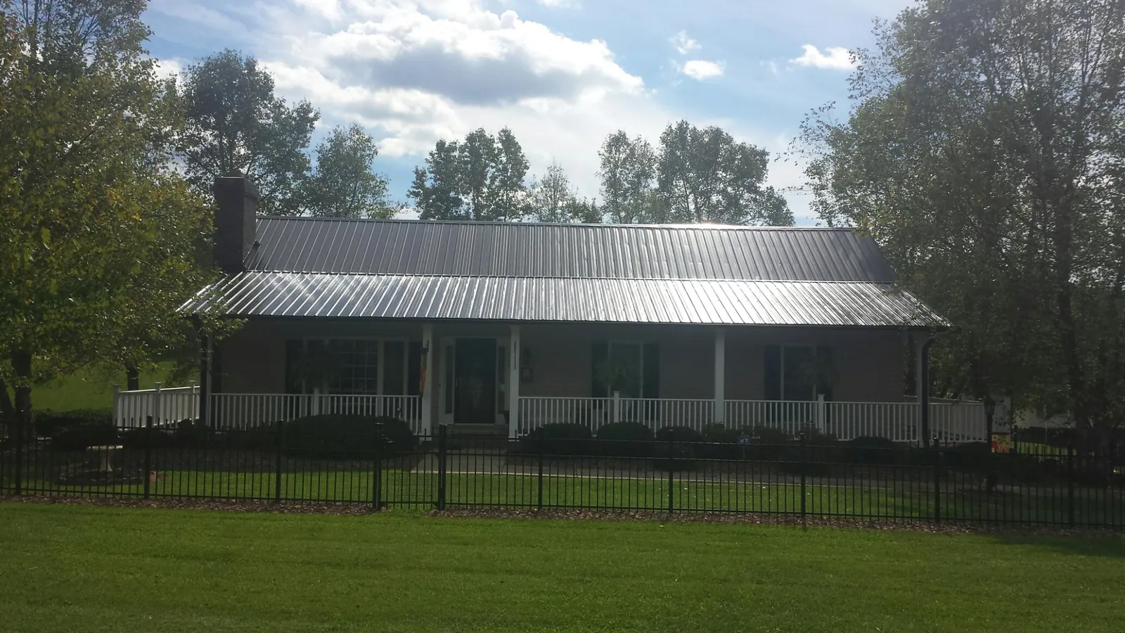 Gray metal roof on a brick ranch with a full width front porch — Gutter Guard Installation work by our crew in Indianapolis