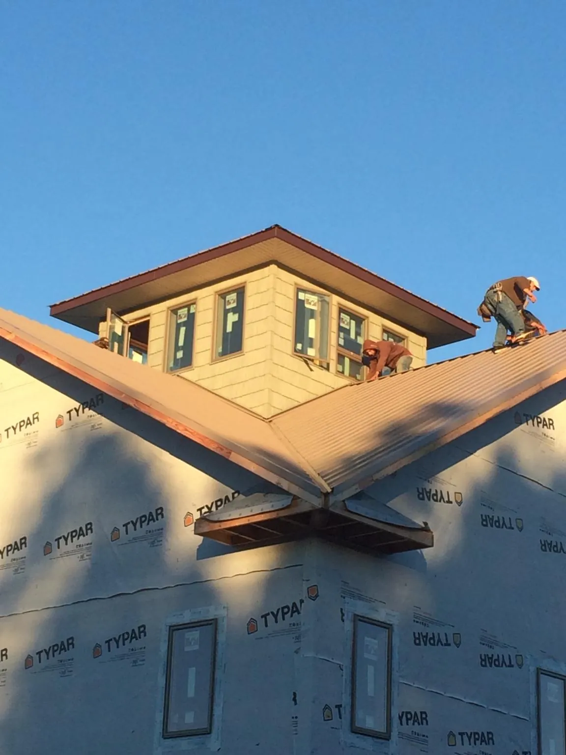 Roofers working around a rooftop cupola on a new metal roof at sunset — Roof Waterproofing in Indianapolis by Roofing Brothers